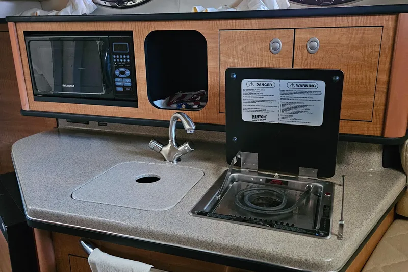 Slide: The Image of 2006 Sea Ray 270 Amberjack galley with microwave, sink, and stove. - 14