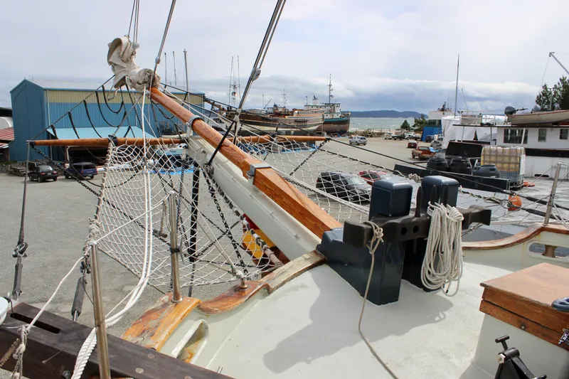 Slide: The Image of 1988 Custom Lahaina Welding Co. Square Topsail Ketch in a shipyard, showcasing rigging and deck details. - 16