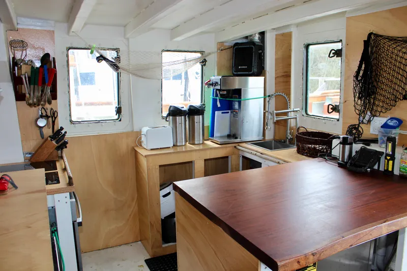Slide: The Image of Interior of 1988 Lahaina Welding Co. Square Topsail Ketch, featuring a compact wooden kitchen area. - 43