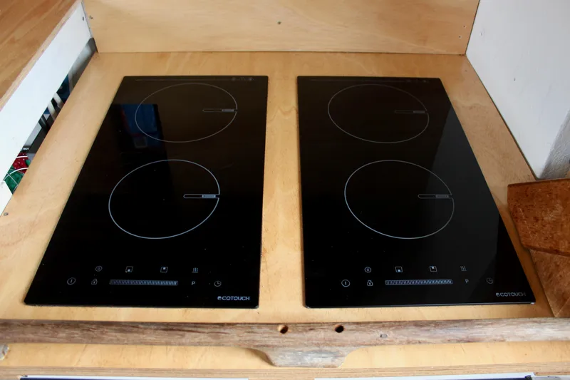 Slide: The Image of Modern induction cooktop with four burners on a wooden countertop. - 46