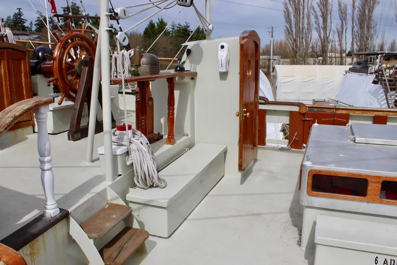 Slide: The Image of 1988 Custom Lahaina Welding Co. Square Topsail Ketch deck with wooden helm and nautical equipment. - 6