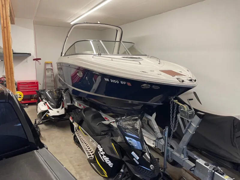 Slide: The Image of 2011 Regal 2750 Cuddy boat stored indoors with snowmobiles. - 15