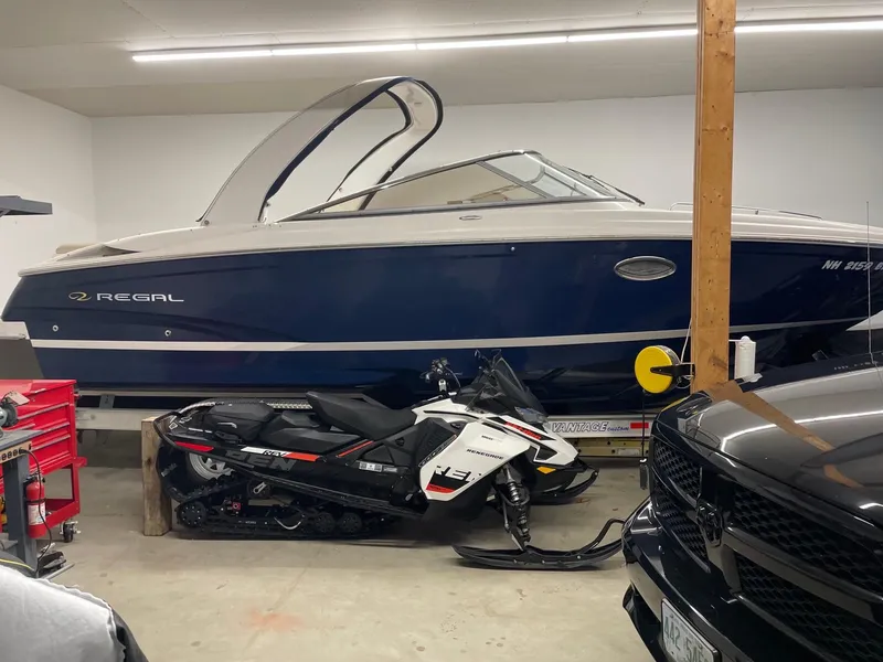 Slide: The Image of 2011 Regal 2750 Cuddy boat in garage with snowmobile and vehicle. - 16