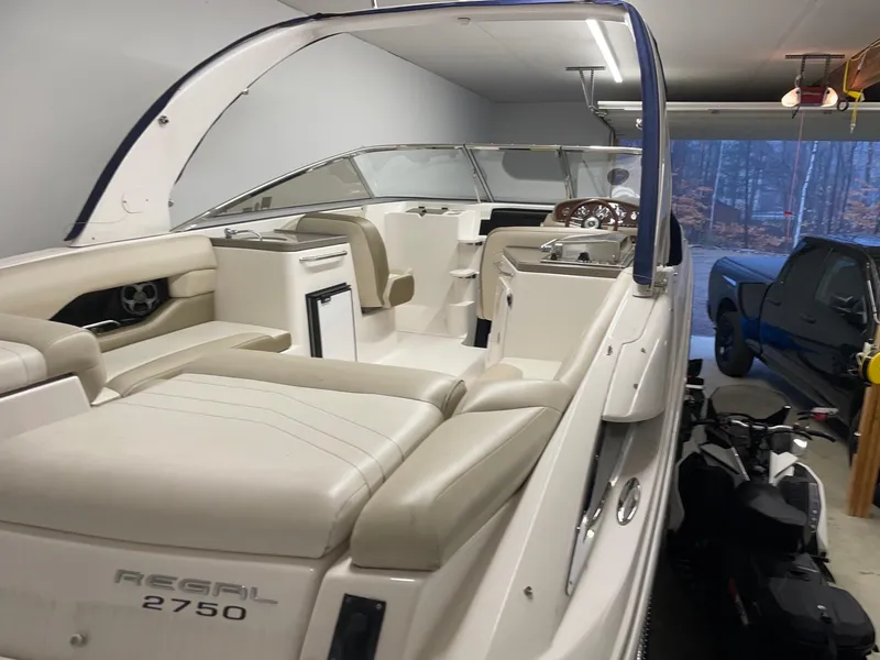 Slide: The Image of 2011 Regal 2750 Cuddy boat in garage, showcasing sleek interior and seating. - 20