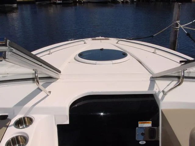 Slide: The Image of 2011 Regal 2750 Cuddy boat deck with open hatch, docked on calm water. - 6