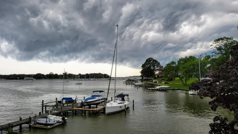 Slide: The Image of Sailboats docked on a river under dramatic storm clouds, featuring a 2011 Hunter e36. - 12