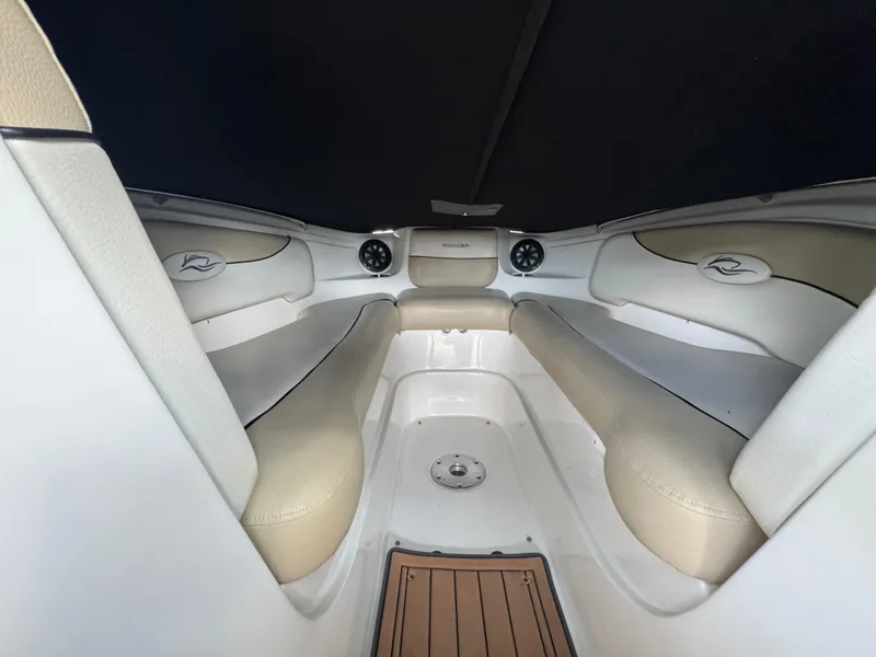 Slide: The Image of 2017 Rinker QX29 BR boat interior with beige seating and wood accents. - 17