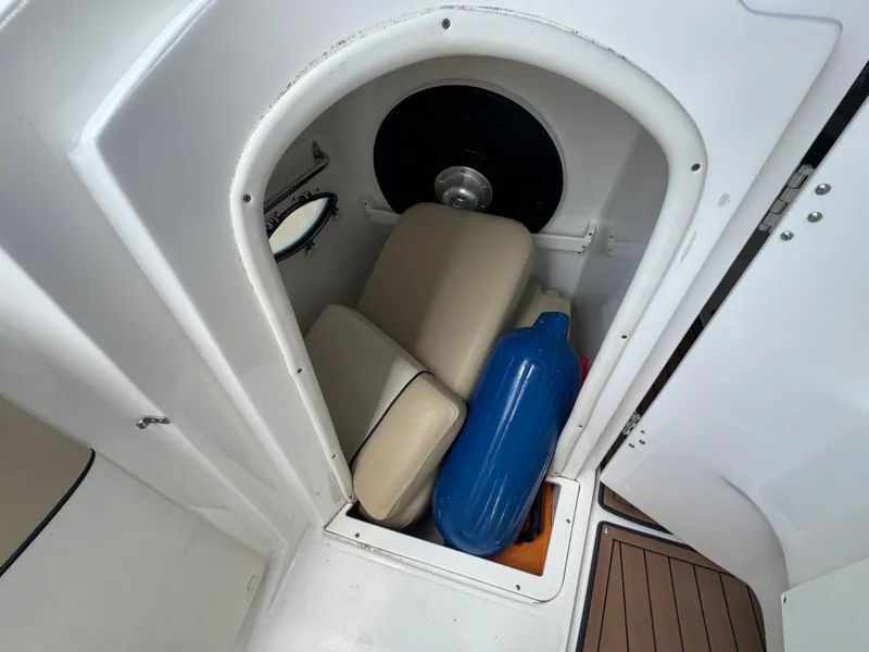 Slide: The Image of 2017 Rinker QX29 BR boat storage compartment with cushions and a blue fender. - 18