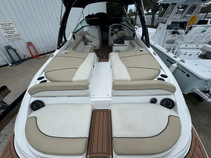 Slide: The Image of 2017 Rinker QX29 BR boat interior with beige seating and wood accents. - 6