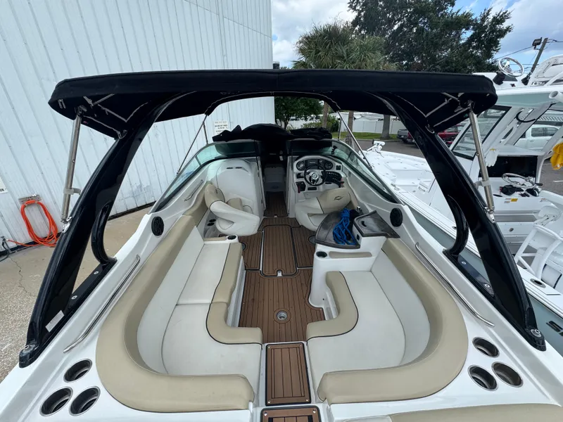 Slide: The Image of 2017 Rinker QX29 BR boat interior with beige seating and black canopy. - 8