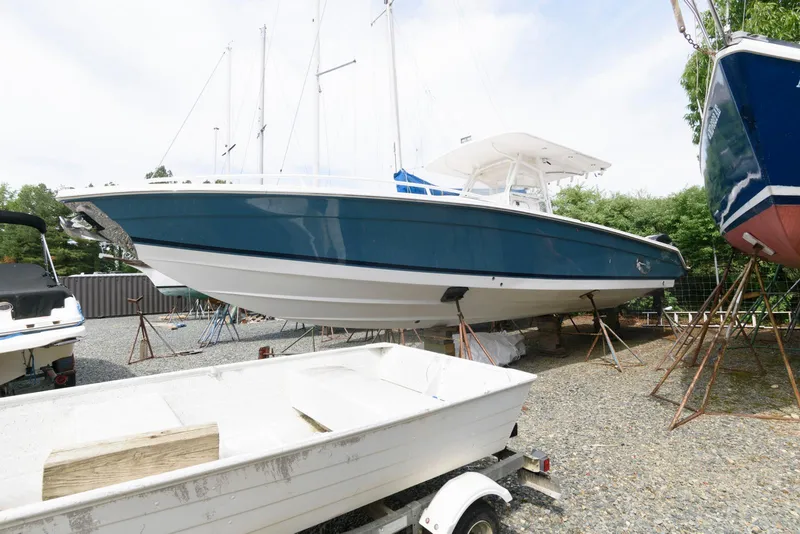 Slide: The Image of 2008 Marlago FS 35 Center Console Cuddy boat on dry dock, blue hull, outdoor storage. - 2