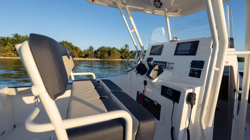 Slide: The Image of 2025 SeaWell 240CC boat interior with modern controls, steering wheel, and seating, near tropical shoreline. - 17
