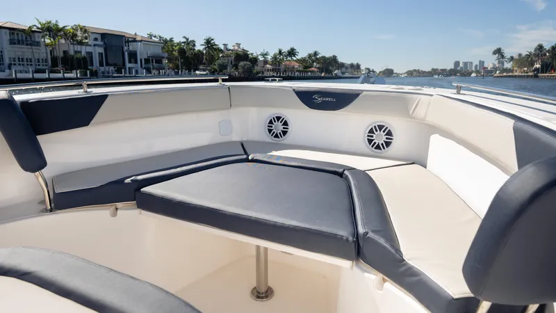 Slide: The Image of 2025 SeaWell 240CC boat interior with cushioned seating, speakers, and waterfront view. - 19