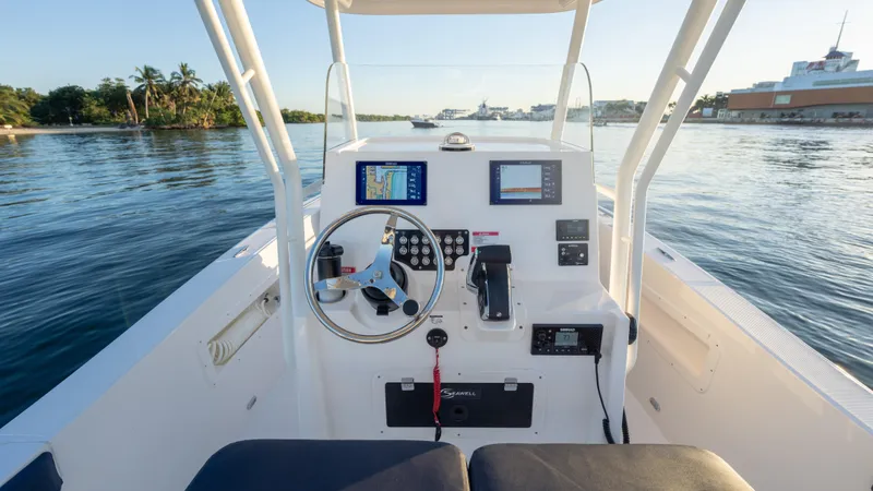 Slide: The Image of 2025 SeaWell 240CC boat cockpit with steering wheel and navigation screens on calm water. - 37