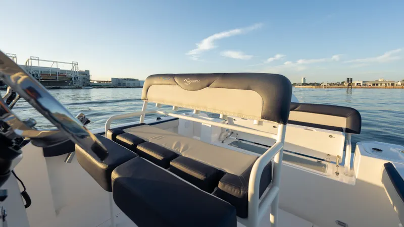 Slide: The Image of 2025 SeaWell 240CC boat interior with cushioned seating, docked by calm waters. - 38
