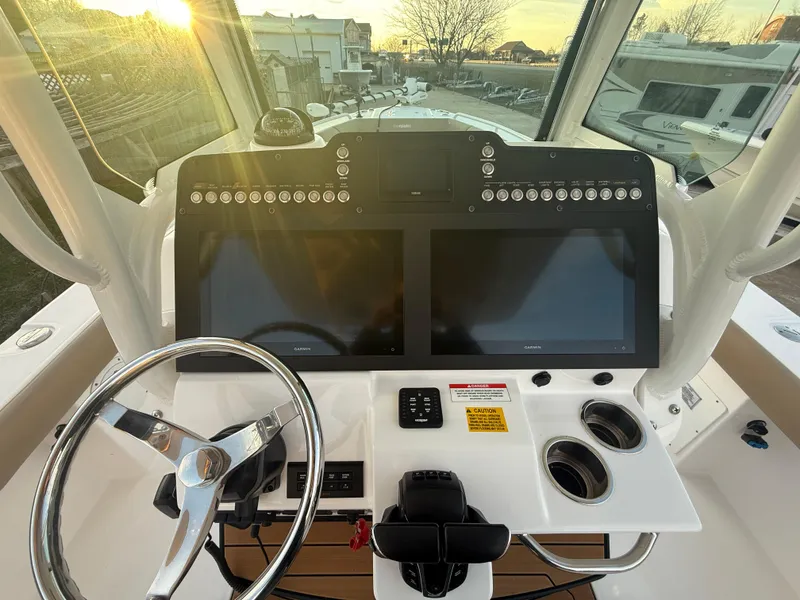 Slide: The Image of 2023 Everglades 273 Center Console boat dashboard with dual screens and steering wheel. - 15
