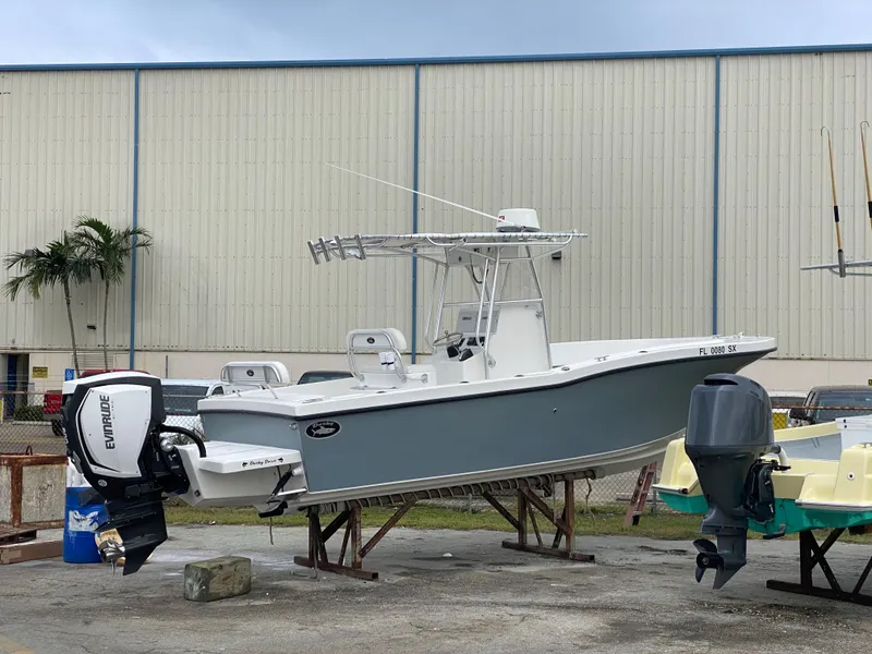 Slide: The Image of 2021 Dusky 252 T boat with Evinrude engine, parked outdoors near a warehouse. - 12