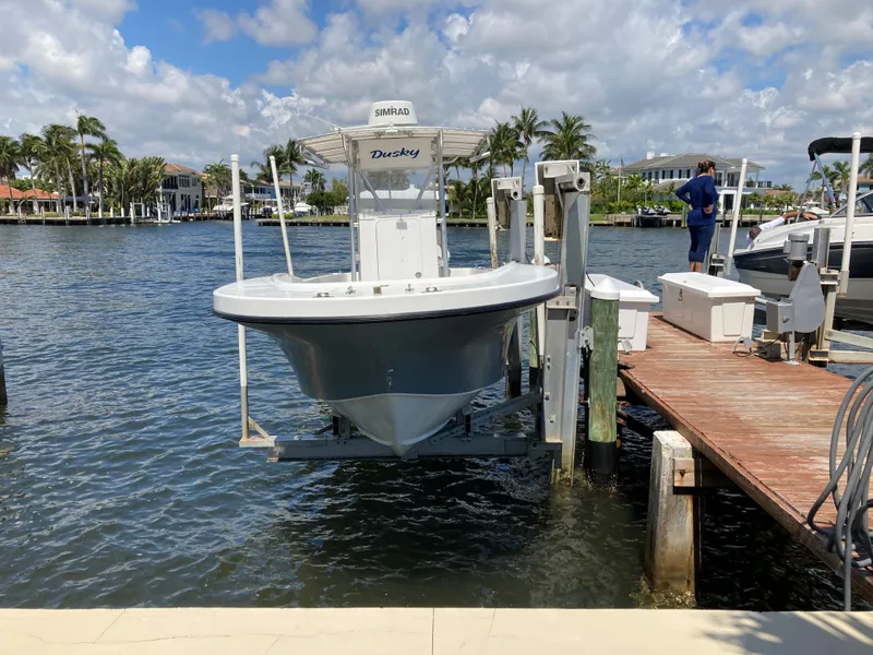 Slide: The Image of 2021 Dusky 252 T boat on lift by dock, under clear sky. - 9