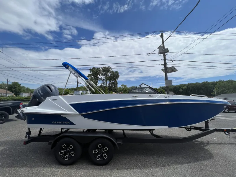 Slide: The Image of 2023 Glastron GTD 220 boat on trailer, blue and white design, parked outdoors. - 3