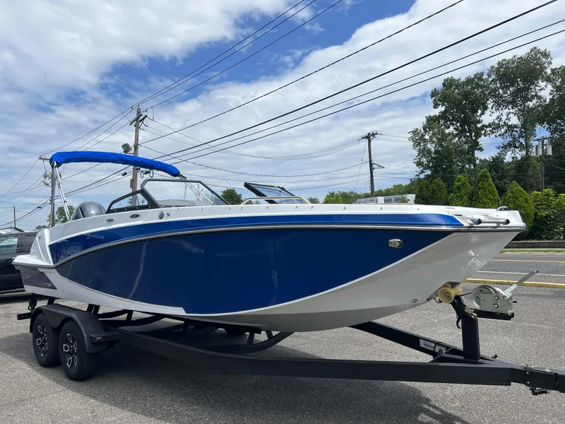 Slide: The Image of 2023 Glastron GTD 220 boat on trailer, blue and white design, parked outdoors. - 4