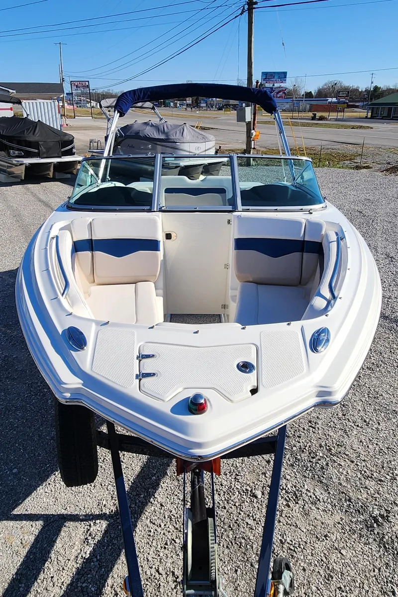 Slide: The Image of 2015 Chaparral 226 SSi boat, white exterior, parked on gravel, sunny day. - 2