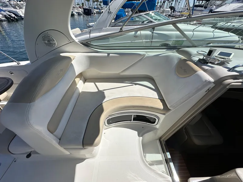 Slide: The Image of 2009 Sea Ray 280 Sundancer boat interior with white seating and marina background. - 15