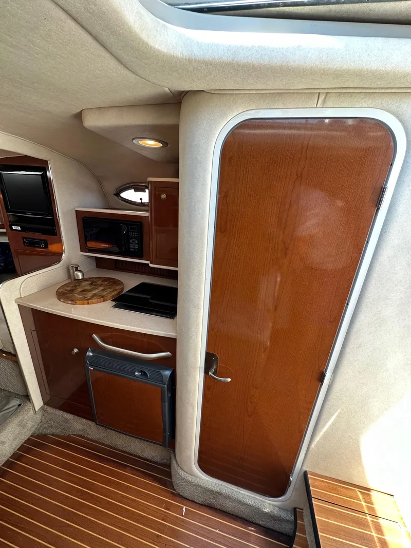 Slide: The Image of 2009 Sea Ray 280 Sundancer cabin interior with kitchenette and wooden cabinetry. - 19