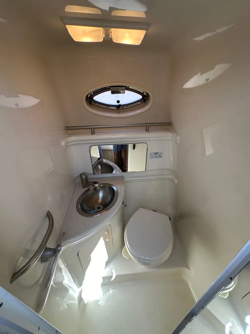 Slide: The Image of 2009 Sea Ray 280 Sundancer bathroom with sink, toilet, and porthole window. - 20