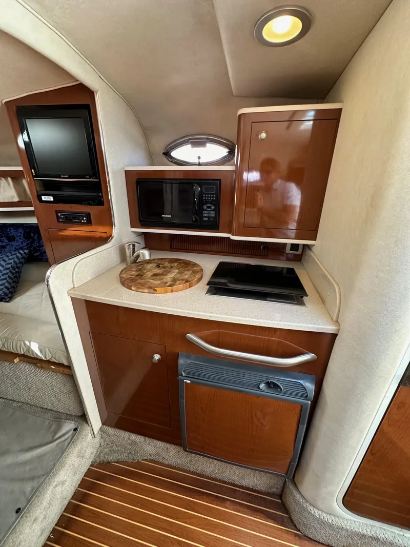 Slide: The Image of 2009 Sea Ray 280 Sundancer interior with kitchenette, featuring microwave and cooktop. - 21