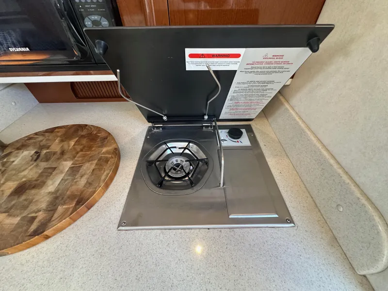 Slide: The Image of Stovetop in 2009 Sea Ray 280 Sundancer yacht kitchen, featuring a single burner and wooden cutting board. - 22