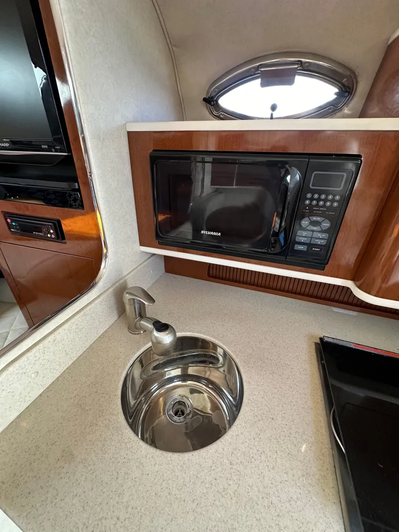 Slide: The Image of Compact kitchen area in a 2009 Sea Ray 280 Sundancer with microwave and sink. - 23