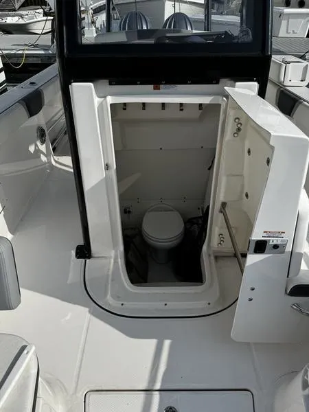 Slide: The Image of 2022 Robalo R272 boat interior with open compartment showing a marine toilet. - 10
