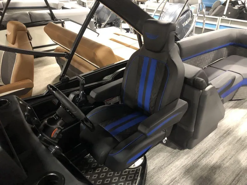 Slide: The Image of 2025 Bennington M Quad Bench 24 MFB boat interior with blue-accented captain's chair and steering console. - 9