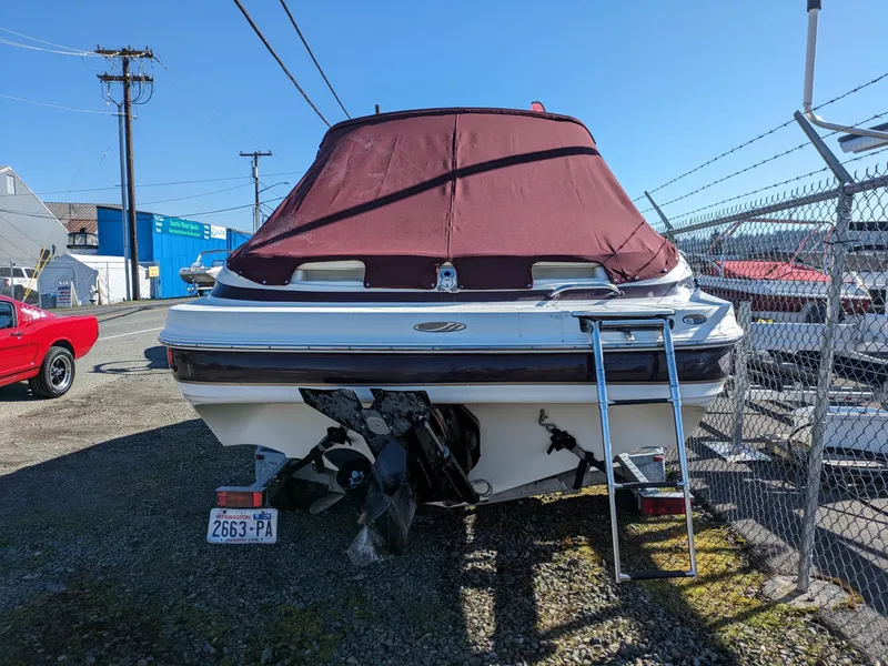Slide: The Image of 2002 Maxum 2100 SC boat with maroon cover, parked near a fence. - 3