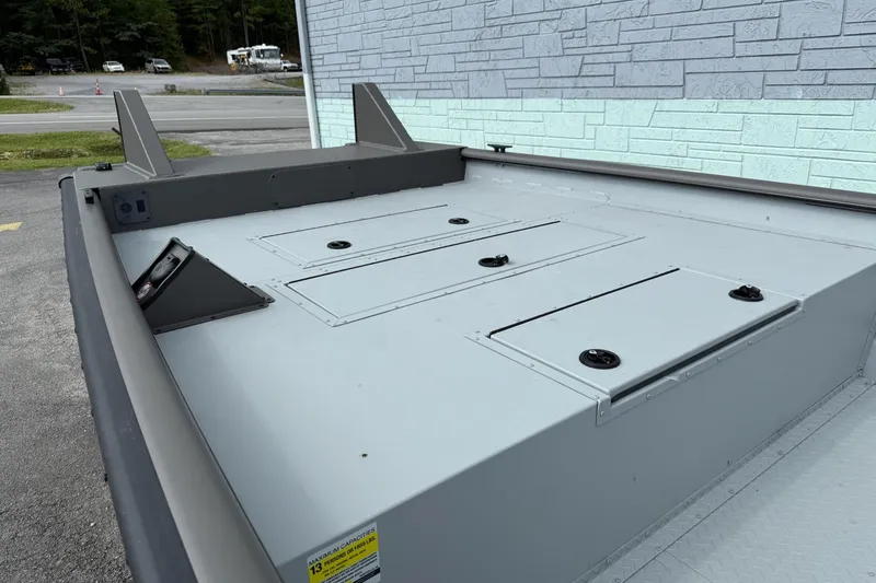 Slide: The Image of 2025 SeaArk 2472 Workhorse 240 boat deck with storage compartments, parked outdoors. - 6