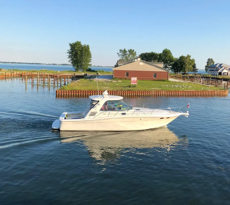Slide: The Image of 2000 Sea Ray 370 Express Cruiser on calm water near a lakeside property. - 0