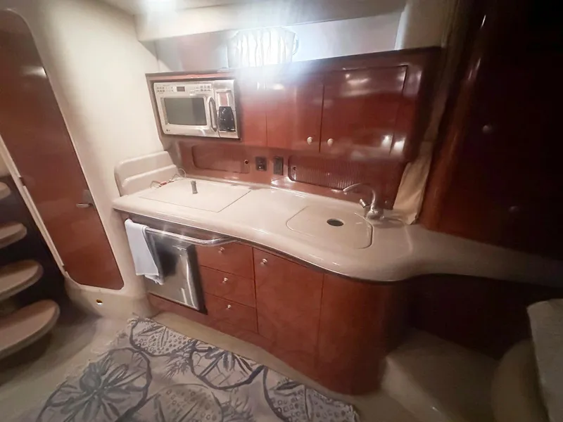 Slide: The Image of 2007 Sea Ray 320 Sundancer kitchen with wood cabinets, microwave, and sink. - 16