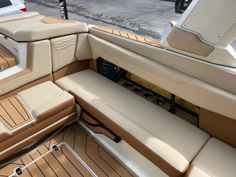 Slide: The Image of 2025 Nautique Super Air Nautique G25 interior with beige seating and teak flooring. - 9