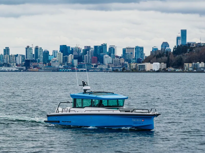 Slide: The Image of 2021 Axopar 37xc Wetbar boat cruising with city skyline in the background. - 15