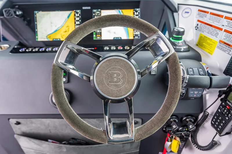 Slide: The Image of Steering wheel and dashboard of 2021 Axopar 37xc Wetbar boat, featuring navigation screens. - 25