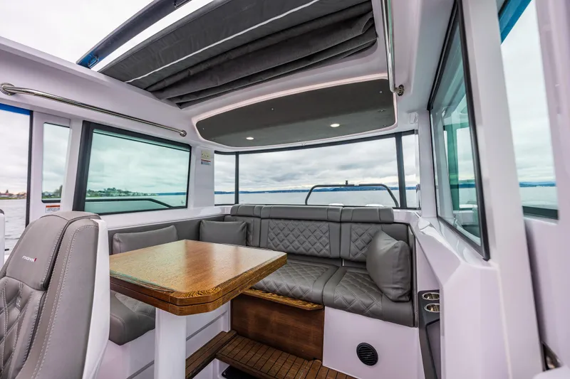 Slide: The Image of 2021 Axopar 37xc Wetbar interior with seating and table, featuring modern design and panoramic windows. - 34