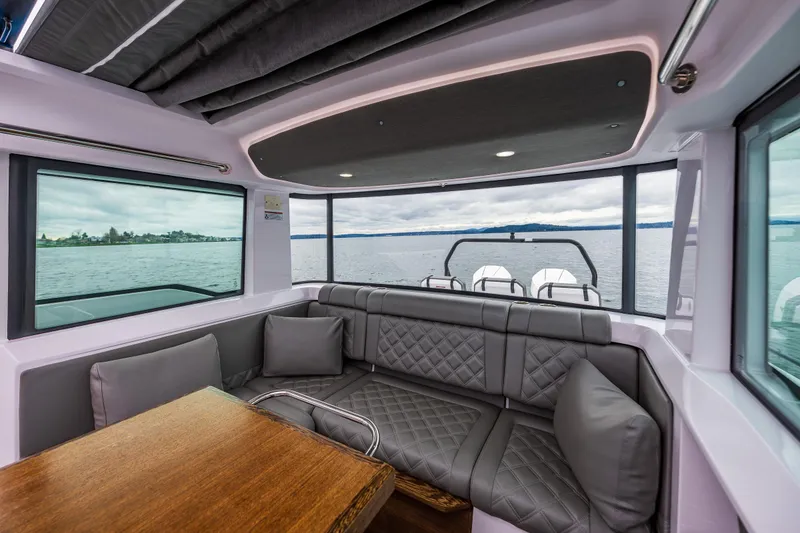 Slide: The Image of Interior of 2021 Axopar 37xc Wetbar with gray seating and wooden table, overlooking water. - 35