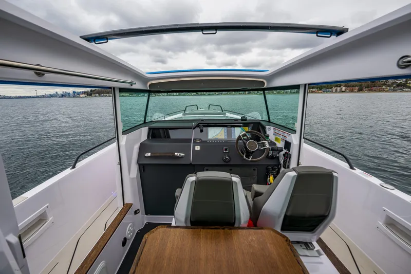 Slide: The Image of 2021 Axopar 37xc Wetbar boat interior with steering wheel and seating on water. - 36