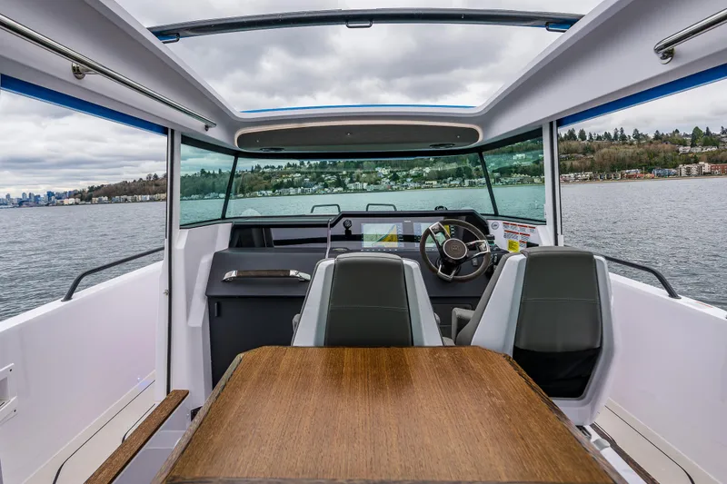 Slide: The Image of Interior view of 2021 Axopar 37xc Wetbar boat with seating and table on a lake. - 37