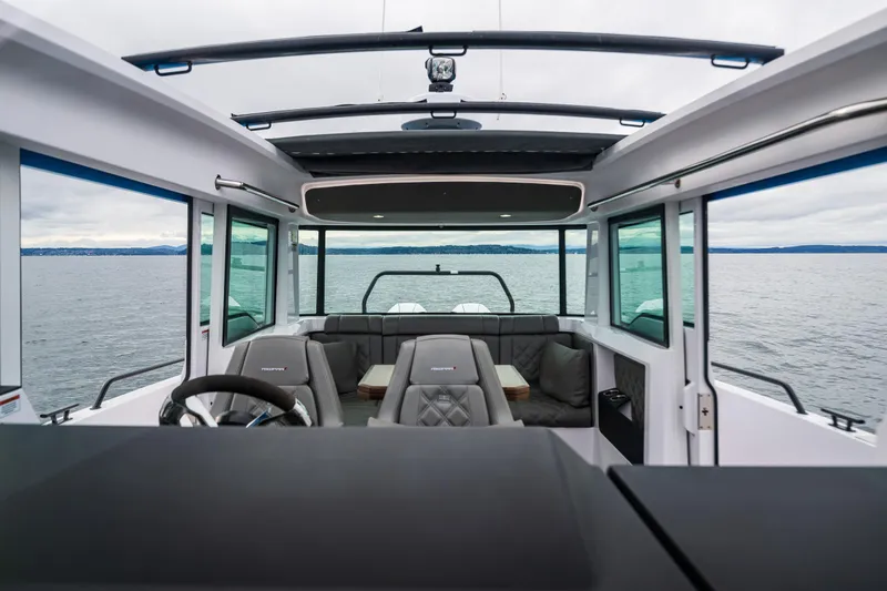 Slide: The Image of 2021 Axopar 37xc Wetbar interior with seating, steering wheel, and panoramic windows on the water. - 46