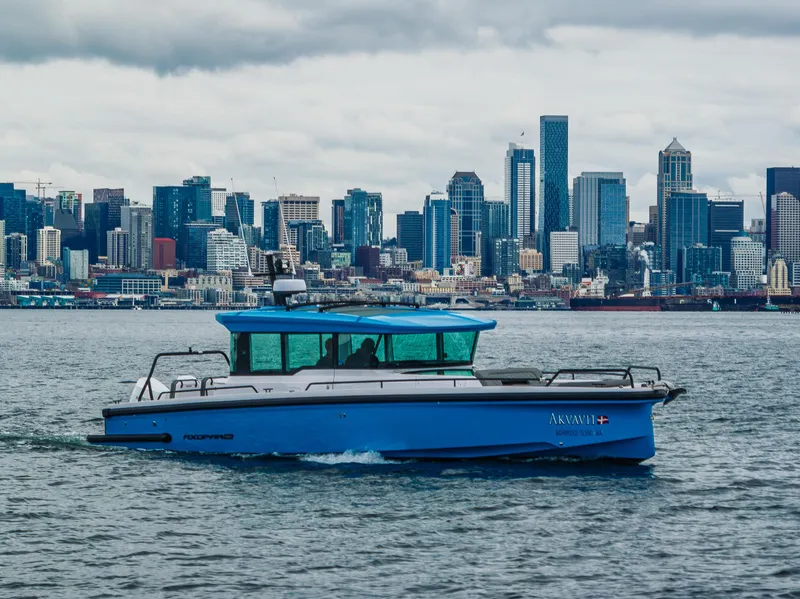Slide: The Image of 2021 Axopar 37xc Wetbar boat cruising with city skyline in the background. - 6