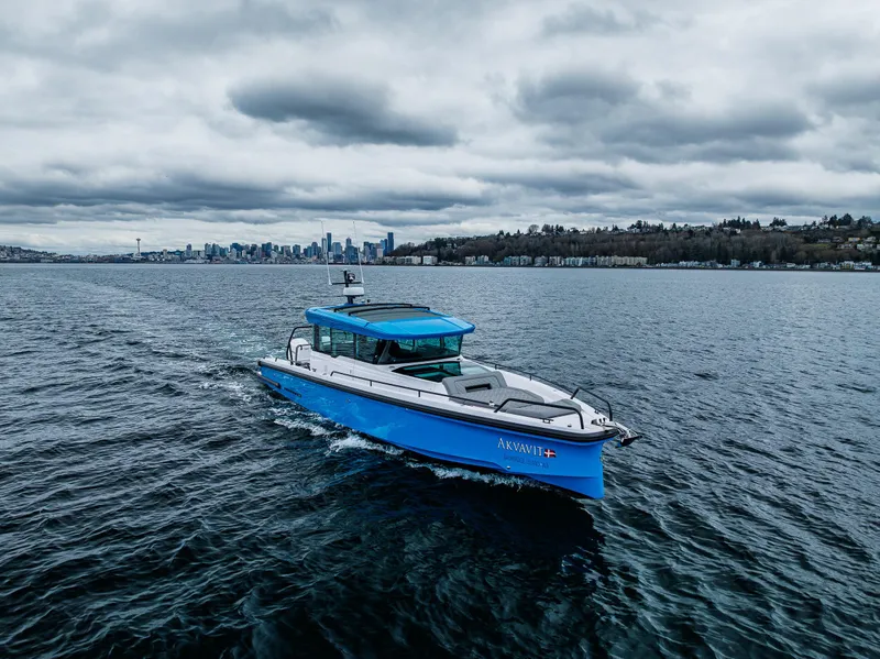 Slide: The Image of 2021 Axopar 37xc Wetbar boat cruising on a cloudy day near a city skyline. - 8
