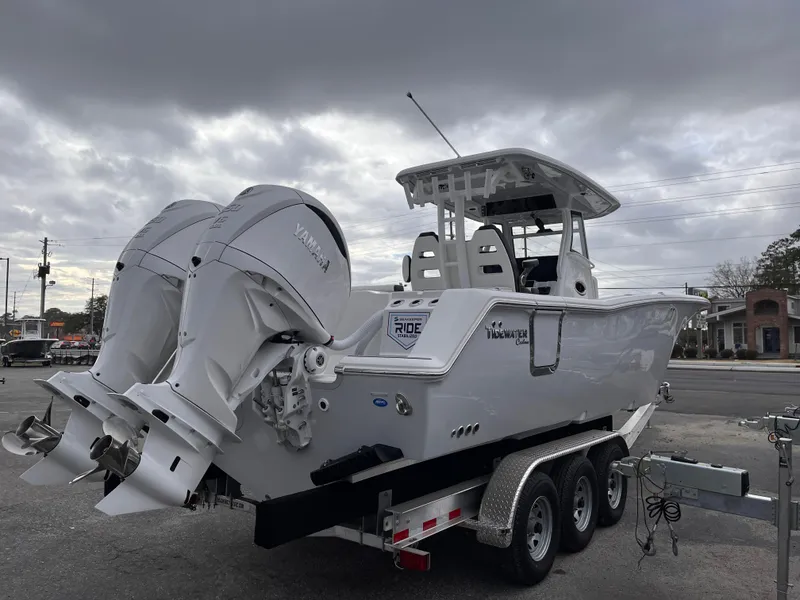 Slide: The Image of 2025 Tidewater 302 CC Adventure boat on trailer, featuring dual engines, under cloudy sky. - 5
