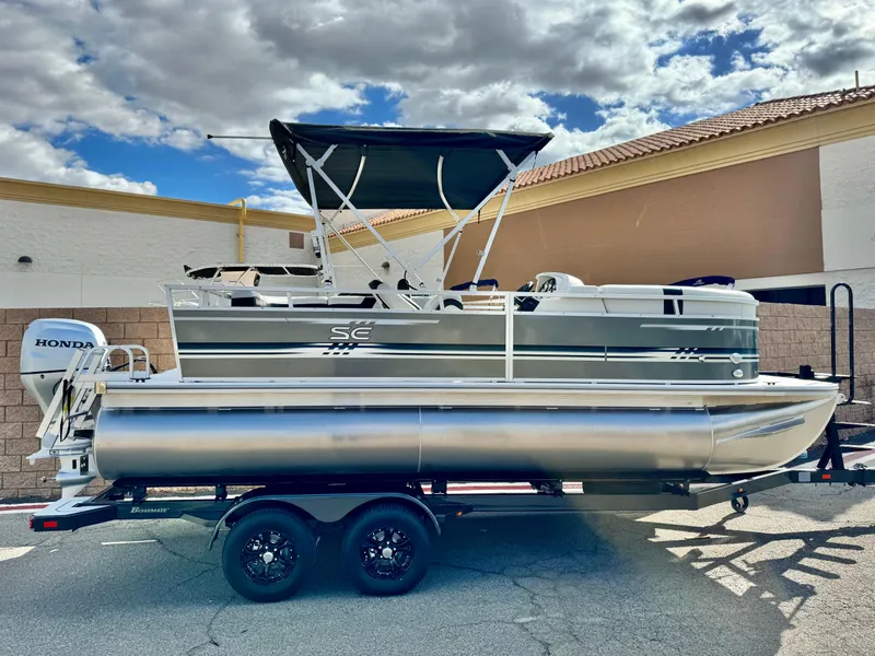 The Image of 2025 Berkshire 20 CRSE pontoon boat on trailer, featuring a Honda outboard motor. - 0