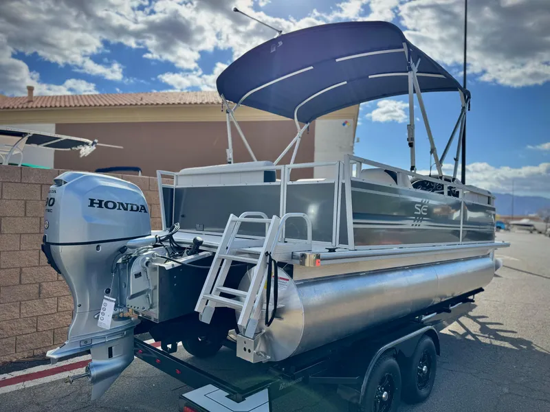 Slide: The Image of 2025 Berkshire 20 CRSE pontoon boat with Honda engine, parked on a trailer under a blue sky. - 6